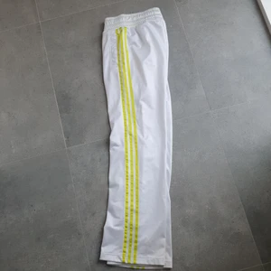 Adidas track pants Respect Me Missy Elliott stl 38 - Vita med neongröna/gula revär.  I använt bra begagnat skick = fint skick. Midja 78 cm Längd 103 cm