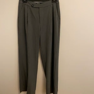 Grå kostymbyxor  - Ett par lågmidjade grå kostymbyxor med en fin detalj i midjan som är använda ett par få gånger. Köpta från Gina tricot för 500 kr. Dom i storlek M men funkar om man är i storlek S också. 