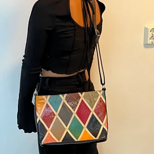 Väska - Rutig färglad väska, med regleringsbart band med dragkedja och en liten inne ficka i väskan. Väskan är secondhand & är i fint skick. Köparen står för fraktkostnaden 