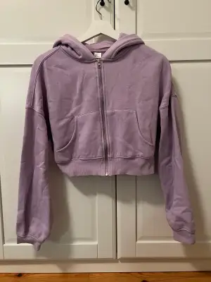 En croppad hoodie med dragkedja i lavendel från H&M. Bara använd några få gånger. Pris kan diskuteras!