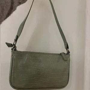 Grön handväska från Kappahl  - Köpte handväskan 2021, är i bra skick och har använt den i skolan i ca en månad, säljer för att jag inte har någon användning av väskan längre.💗