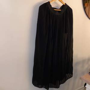 Lång svart plisserad kjol i strl S-M Kortare underkjol. Genomskinlig/seethrough överkjol.  Köparen betalar frakten 