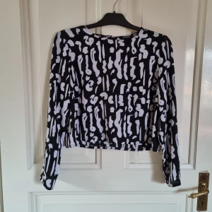 Skir croptop/blus från Monki - Skir topp från Monki, 100% polyester. Kortare i modellen.  Storlek 42, passar mindre också.   Grå/svart. Fint skick, inget att anmärka på. 