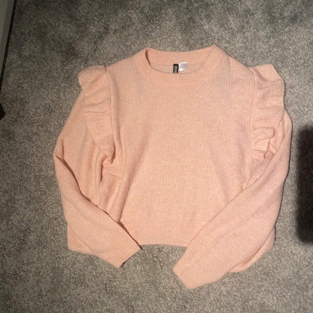 En rosa stickad tröja med volanger på armarna som aldrig är använd. Strl XS . Pris:80 kr. Stickat.