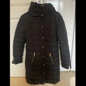 Knälång jacka - En vinterjacka i storlek 38 som går ungefär till knäna. Guldiga detaljer samt hakar för att sätta i medföljande skärp🦋 hör av er vid funderingar eller intresse💕spårbar frakt på 49kr tillkommer📦obs skriv till mig innan ni klickar på köp nu 🫶