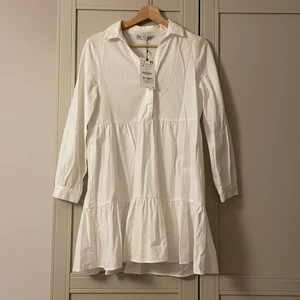 Vit klänning  - Fin vit somrig klänning i skjortmaterial. Aldrig använd. Nytt skick.