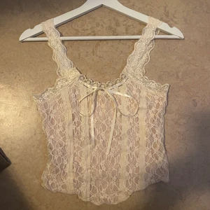 Vit topp  - Vit topp med extra detaljer på, jättefin med snöre och mycket spets detaljer. säljer då den är lite stor vid brösten. denna passar för xs-s men hade kunnat passa M då den är stretchig