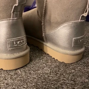 Uggs - Grå uggs med silvet på baksidan, Använda ett fåtal ggr. strl 39 men passar mig som har 38 vanligtvis. Köpta för 2199kr i vintras, säljer för 1900kr💘