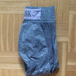 Gymshark highwaist flex leggings i storlek S, gråa med ljusrosa logga ovanför rumpan, knappt använda, fint skick.