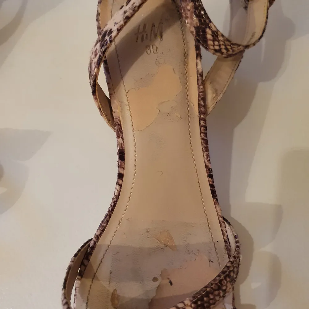 Sandaletter med klack ca 6cm. Ankelremmar, läderimitation, strl 39. Märke H&M. Använda 1 gång. innersulan på vänster sko har lite skador, se bild. Därav det låga priset, annars är skorna i bra skick, klacken ser oanvänd ut.. Skor.