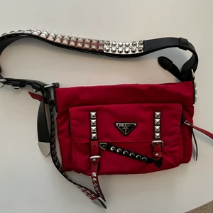 Prada väska - Väska inköpt på Prada-outleten i Malaga förra sommaren 💓 Ordniare fullpris ligger på ca 13.000kr men jag säljer för bara 5500kr då jag vill ha en snabb affär. Den är i helt nytt skick, inga skador osv! Kvitto, påse och allt som kom med vid köpet finns såklart kvar och följer med i köpet! Går bara att ha 3 bilder på Plick men skickar gärna fler - skriv privat så fixar jag det 🥰 sjukt cool med nitar och flera olika delar som ser ut som ”bälten” 