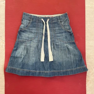 Jeanskjol - Älskar denna jeanskjol. Kjolen är i 146 i barnstorlek. Passade dock mig när jag hade byxstorlek runt 32/34. Y2k känsla får jag av detta plagg. Så skönt material! Har dragkedja på vänster höft🌷kontakta mig för mått!🫶
