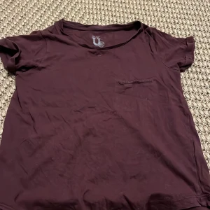 T-shirt - En vinröd tshirt jag säljer då den är för liten den har också en liten ”ficka” där fram