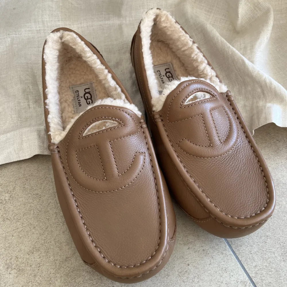 UGG x Telfar loafers with shearling lining  Embossed logo on front, Leather piping, Tonal stitching, Round toe, Shearling lining, Embossed logo on footbed, EVA midsole, No closure   Completely new and unworn :)  Unfortunately no box - just the bill  . Skor.