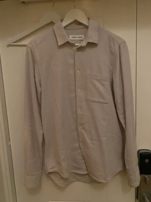Samsøe Samsøe skjorta - Väldigt fin skjorta i en stilren färg och utmärkt skick. Men kan styla den utan tröja under men även med en t-shirt under. Den är i ett skönt material som gör att de känns mer som en tröja än en skjorta som kanske inte alltid är så bekväm. Äggvit färg.