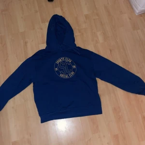 Cubus marinblåa hoodie med gul text, sports club logo, social club logo - Cubus marinblåa hoodie med gul text detaljer. Original pris 200kr