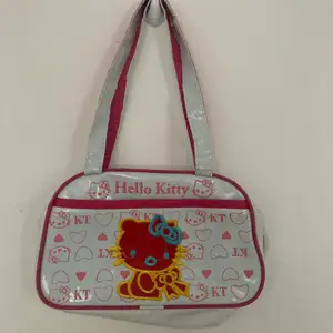 As söt Hello Kitty väska från ca 2009! Lite sliten på banden därav priset men funkar som vanligt!! Längd: 24cm Höjd: 15 cm Bredd: 8cm