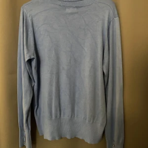 Blå polo tröja  - En blå polotröja med hög krage och detaljer på armarna 