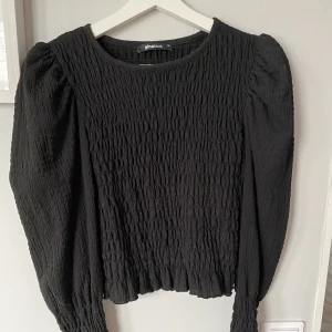 Svart tröja - Svart tröja med liten puffärm och ”resår” längst ner på armarna. Tröjan är lite nopprig annars i fint skick