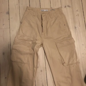 Cargopants - Beige cargobyxor från Bershka. De saknar en knapp då det lägre priset. De är använda med inga skador förutom den saknade knappen.