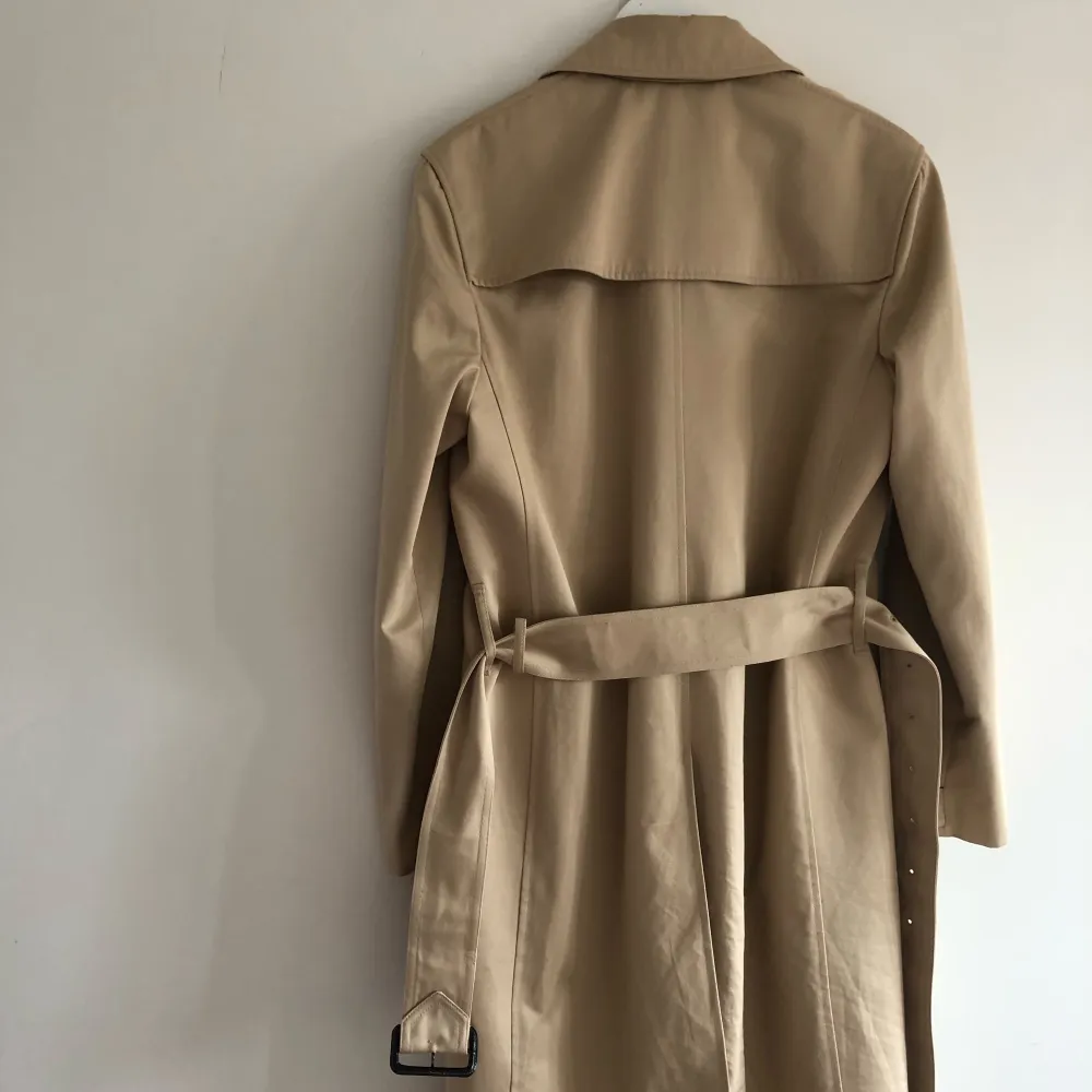 Trenchcoat i klassisk rak passform med bälte i midjan. Rocken ner till knäna om man är runt 175 cm lång. Rocken är även vattenavvisande . Jackor.