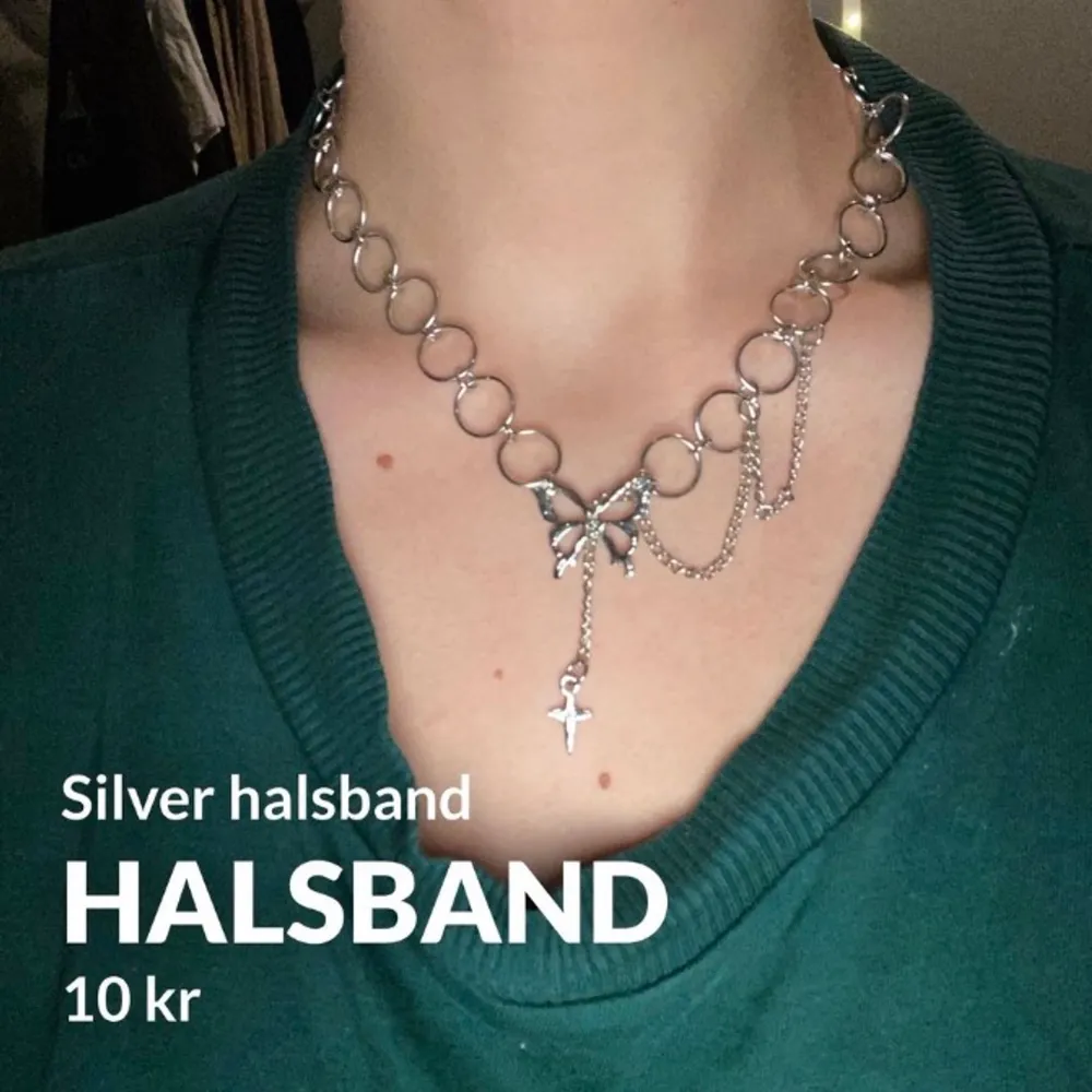 Silvrigt halsband gjord av ringar som sitter ihop. Längst fram sitter en fjäril och en stjärna som hänger nej. Bredvid finns en liten kedja.. Accessoarer.