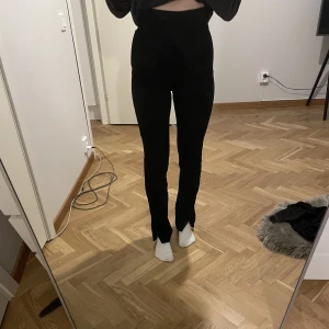 Kostymbyxor med slit - Byxor med slit och väldigt högmidjade. Dragkedja vid sidan och bred resor runt midjan. Frakten ingår inte 