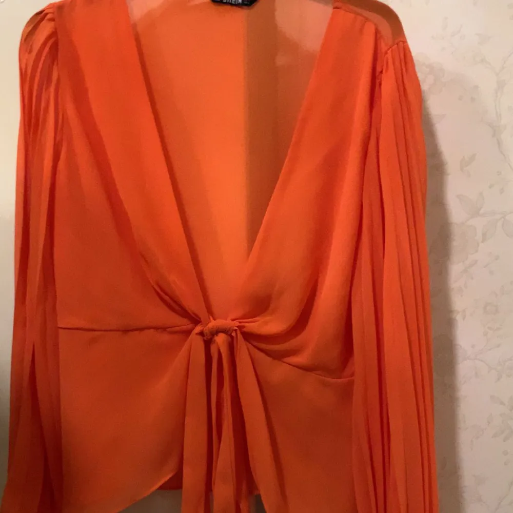 En orange tunn bluse som sticker ut och en väldigt uppkläd bluse . Blusar.