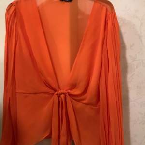 En orange tunn bluse som sticker ut och en väldigt uppkläd bluse 