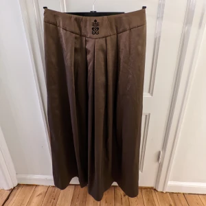 Lång kjol - Oanvänd långkjol i mycket fint material. Prislapp finns kvar på varan. Välsydd med fina detaljer. Slits med gulddetalj. Perfekt till nyår! Nypris: 1750 kr