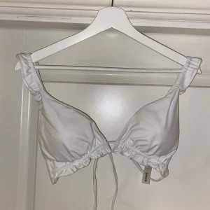 Vit bikinitopp - Denna vita bikinitoppen är oanvänd då den inte passade mig, volanger på axelbanden och knyte i ryggen🫶🏼SÅ fin! Strl är L men passar typ en B eller C kupa bäst och omkretsen är ju väldigt justerbar pga knyt bandet i ryggen☺️