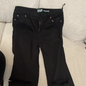 Bootcut Jeans - Svarta bootcut jeans med distress vid knänen. Högmidjade str 40
