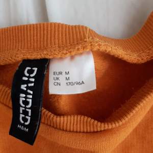 Aldrig använd, strl M köpt på H&M. Det en mag tröja. Ser orange ut men är senaps gul. Materialet är bomull och polyester.