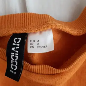 Aldrig använd, strl M köpt på H&M. Det en mag tröja. Ser orange ut men är senaps gul. Materialet är bomull och polyester.