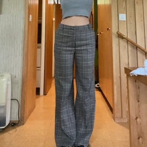 Kostymbyxor - Rutiga ish kostymbyxor i mörkgrå! Köpta på second hand men är i superbra skick! Dem faller ganska rakt men är lite utsvängda vid anklarna! Står ingen storlek på dem men skulle säga M, men passar som oversize på en S ( som jag)