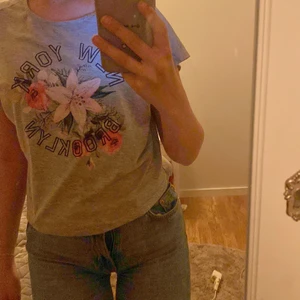 T-shirt med en blomma på - En T-shirt med en blomma på där det står new york Brooklyn på lite utsvängd i armarna