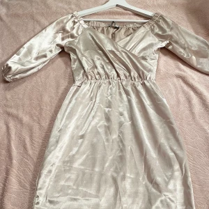 Beige silkes klänning BikBok - Beige färgad kort klänning i material av silkes från BikBok Str XS. Oanvänd med original pris 299 kr, säljs för 60 kr. Frakt ingår ej. 