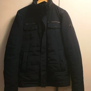 J. Lindeberg - Bailey 56 Structured Poly - En riktig snygg höst/vinterjacka av väldigt hög kvalitet.   Extremt gott skick.  Köptes för 2999kr.