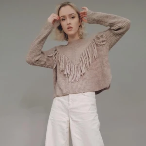 Stickad tröja med fransar - Supermysig beige/ljusbrun stickad tröja med fransdetalj. 25% ull. Toppenskick, använt ett fåtal gånger. Väldigt smickrande passform! Storlek M, passar snyggt på XS-M.