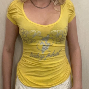 BabyPhat T-shirt - Gul T-shirt med snörning och silvrigt tryck från Baby Phat. Fint skick.