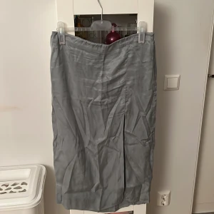 Högmidjad turkos kjol - Högmidjad turkos kjol från H&M med slit och dragkedja på sidan.