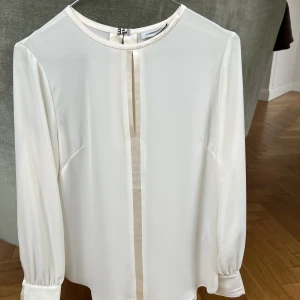 Blus  - J. Lindeberg blus i storlek 34. Färg offwhite. Fina detaljer fram, bak och vid ärmar.  Aldrig använda. 