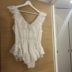 Vintage babydoll - Superfin vintage babydoll, body i vit satin och spets med rosa detaljer.  Är använd, ej av mig, men är i fint skick. Har en liten skråma i spetsen på nedre baksida, se gärna bild!  Troligen en storlek M-L! 