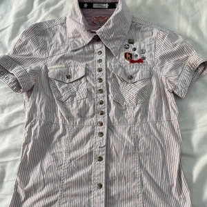 Vintage skjorta från Khujo TM vintage - Vit skjorta med rosa ränder från Khujo TM vintage. Köpt secondhand och säljer pga inte min stil! Väldigt trendig tröja skulle jag säga själv! Storlek M men mer som en S/M