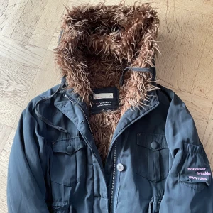 Odd Molly jacka (höst/vinter) - Odd Molly jacka med många fina detaljer. Lite blank i tyget vilket är svårt att fånga på bilden. Hela jackan är fodrad med fuskpäls (samma som i luvan). Stl 2 (38/40)