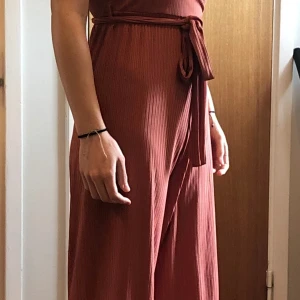 Ljusrosa jumpsuit - Ljusrosa byxklänning/ jumpsuit. Jätteskön byxklänning som jag använt två gånger så den är i väldigt bra skick!! Tror jag köpte från Nakd. Kostade runt 500-600kr. Säljer den för 200kr 