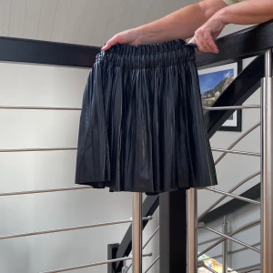 Plisserad skinnkjol  - En super trendig skinnkjol med inbyggda shorts! 