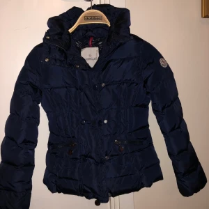 Moncler jacka - En äkta Moncler jacka för barn, storlek 140. En jättefin jacka i barinblå. Denna jacka har endast används ett fåtal gånger och är i jättegod skick! Har ni frågor och funderingar är det bara att höra av er! 