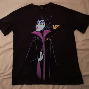 MÖRKGRÅ tshirt från Bershka med Maleficent på i stretchigt tyg. Trycket har en lite sliten grungy look, den var skapad så, det har inte slitits bort med tiden. Den är 48cm bred och 64cm lång.