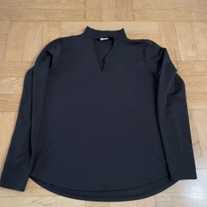 Topp - Svart topp med urringning framtill. 